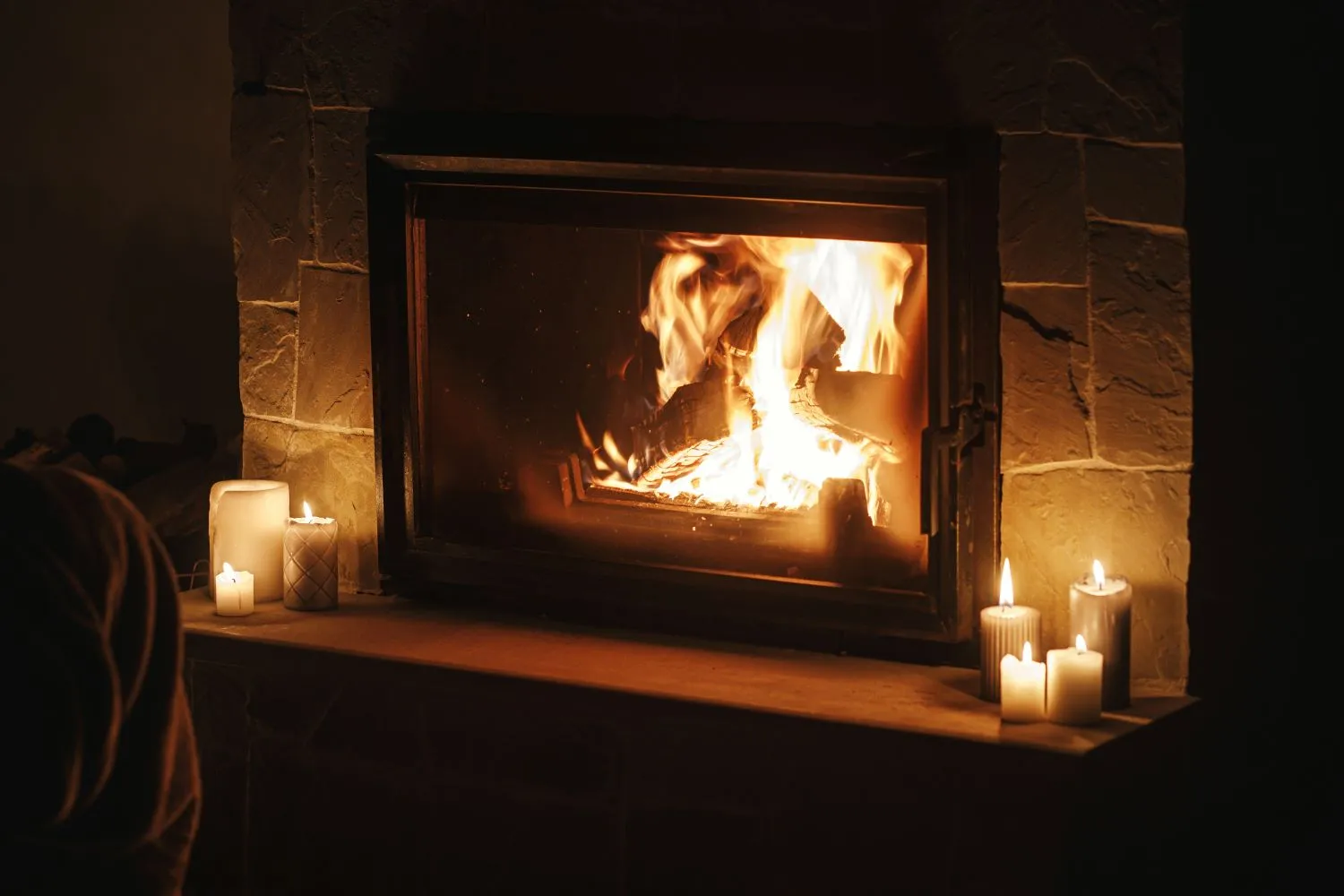 cosy burning fireplace using kiln dried logs and candles in dark evening